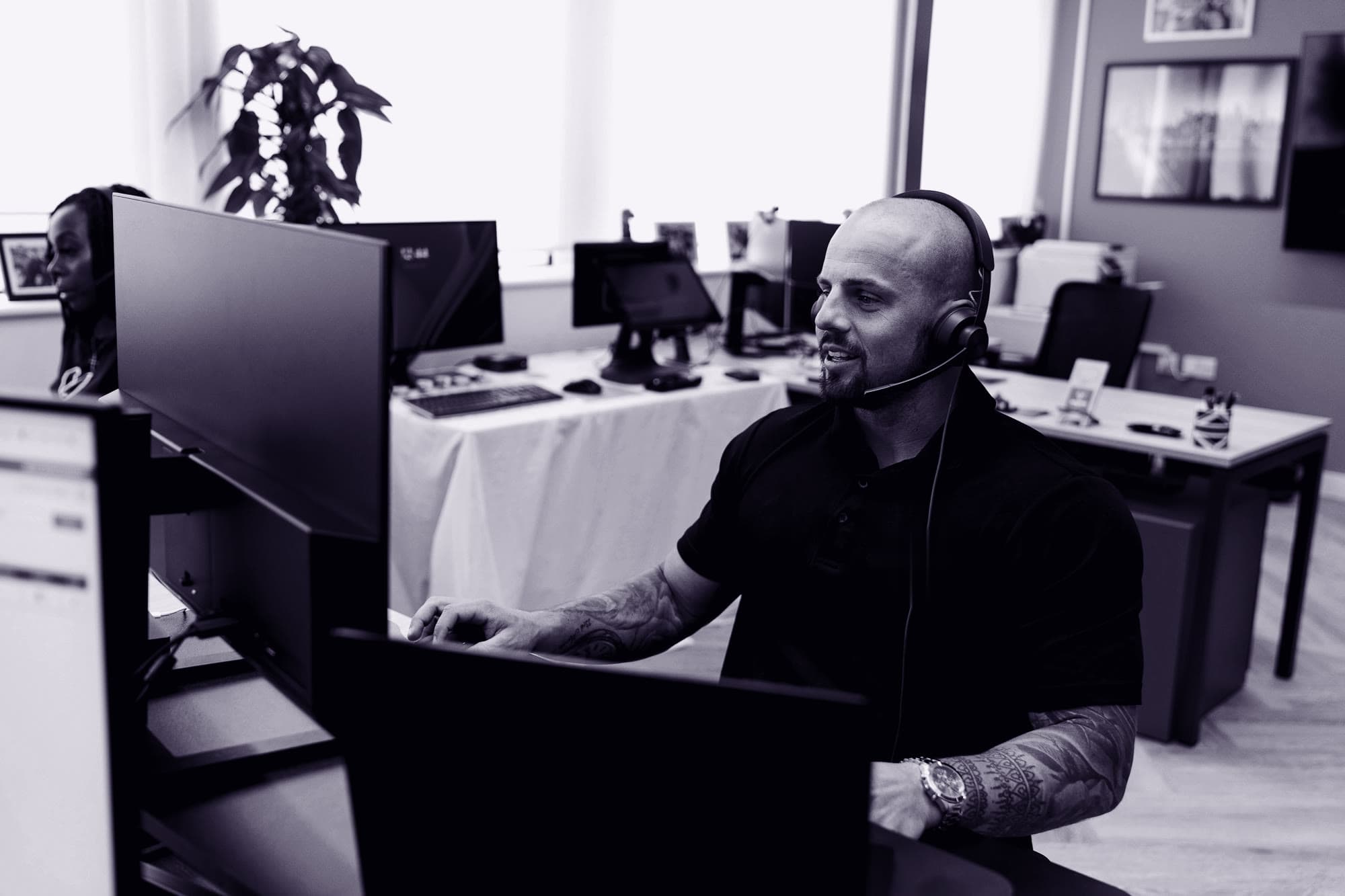 A BDC agent on a headset answering a customer at a dealership desk